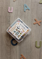 ABC & 123 magnetic letters and numbers in a clear storage box, surrounded by colourful letters on a wooden floor