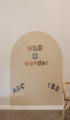 Magnetic letters spelling WILD + wonder with ABC and 123 on the Arlo Beige Wonder Arch