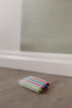 Dust-free chalk sticks in green, pink, blue and red holders on a wooden floor beneath the Wonder Arch