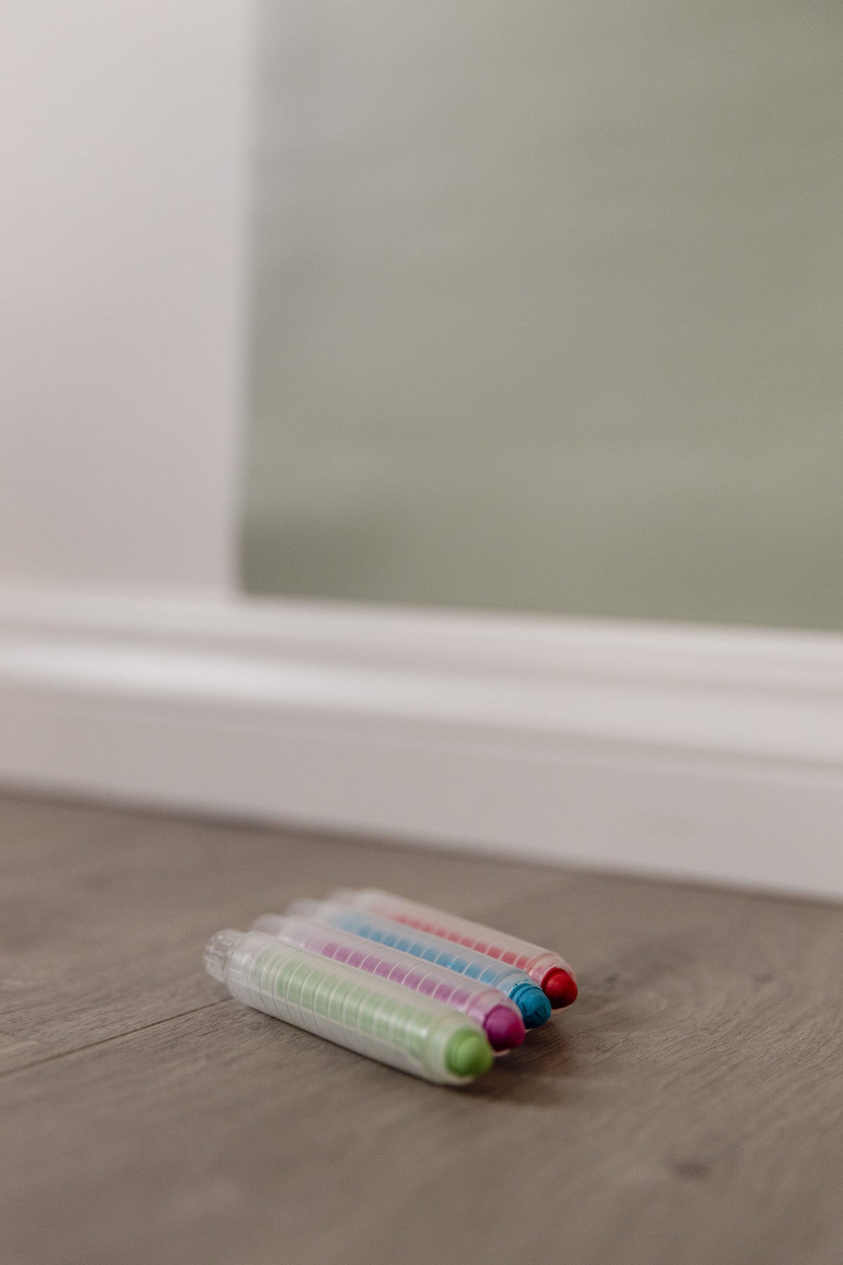 Dust-free chalk sticks in green, pink, blue and red holders on a wooden floor beneath the Wonder Arch