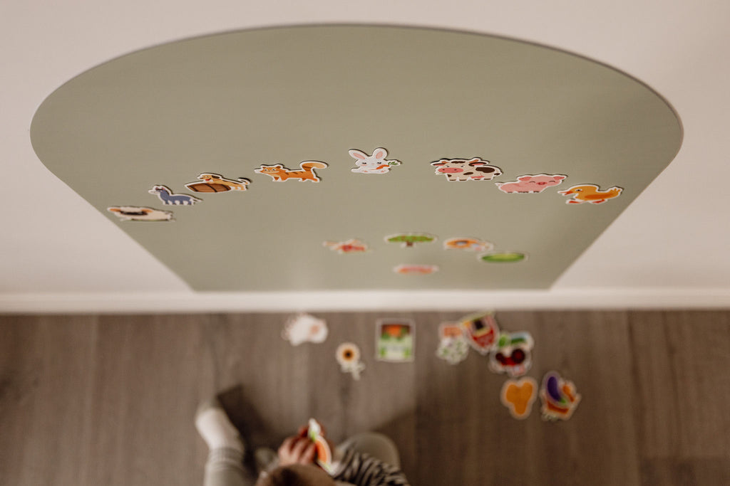 Overhead view of a toddler sorting farm magnets on the floor beneath the Wonder Arch