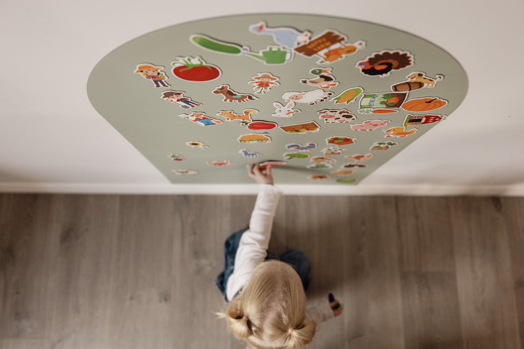 Overhead view of a toddler reaching up to a Wonder Arch covered in farm magnets