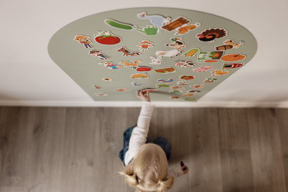 Overhead view of a toddler reaching up to a Wonder Arch covered in farm magnets
