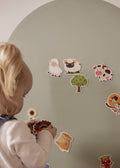 Toddler placing farm animal magnets on the Lily Sage Wonder Arch
