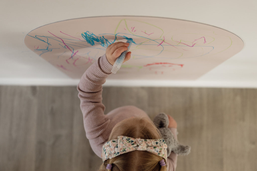 Top-down view of a child drawing colourful scribbles on the Isla Blush Wonder Arch
