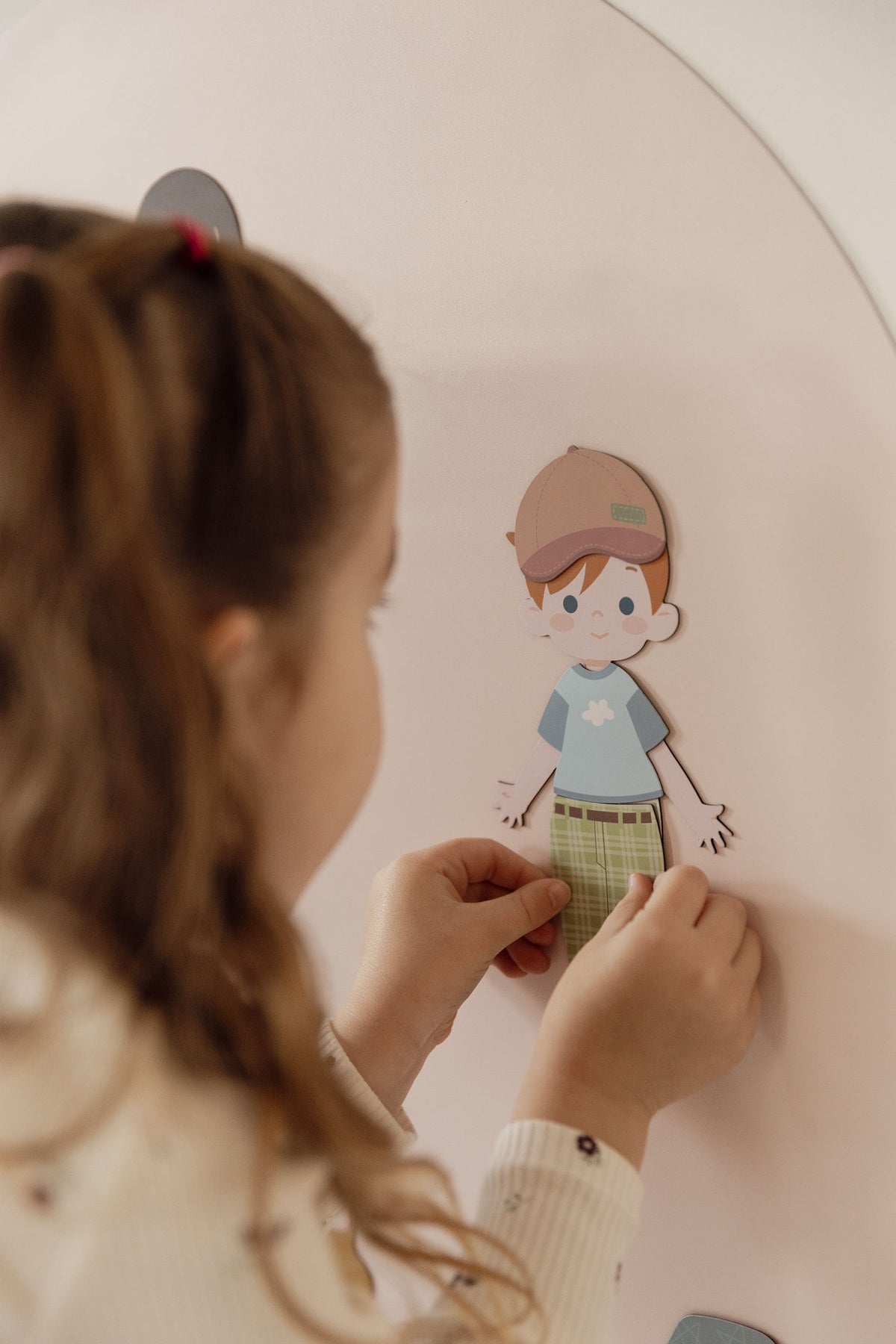 Child dressing a magnetic dress-up character on the Isla Blush Wonder Arch
