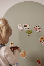 Close-up of a toddler placing farm animal magnets on the Lily Sage Wonder Arch