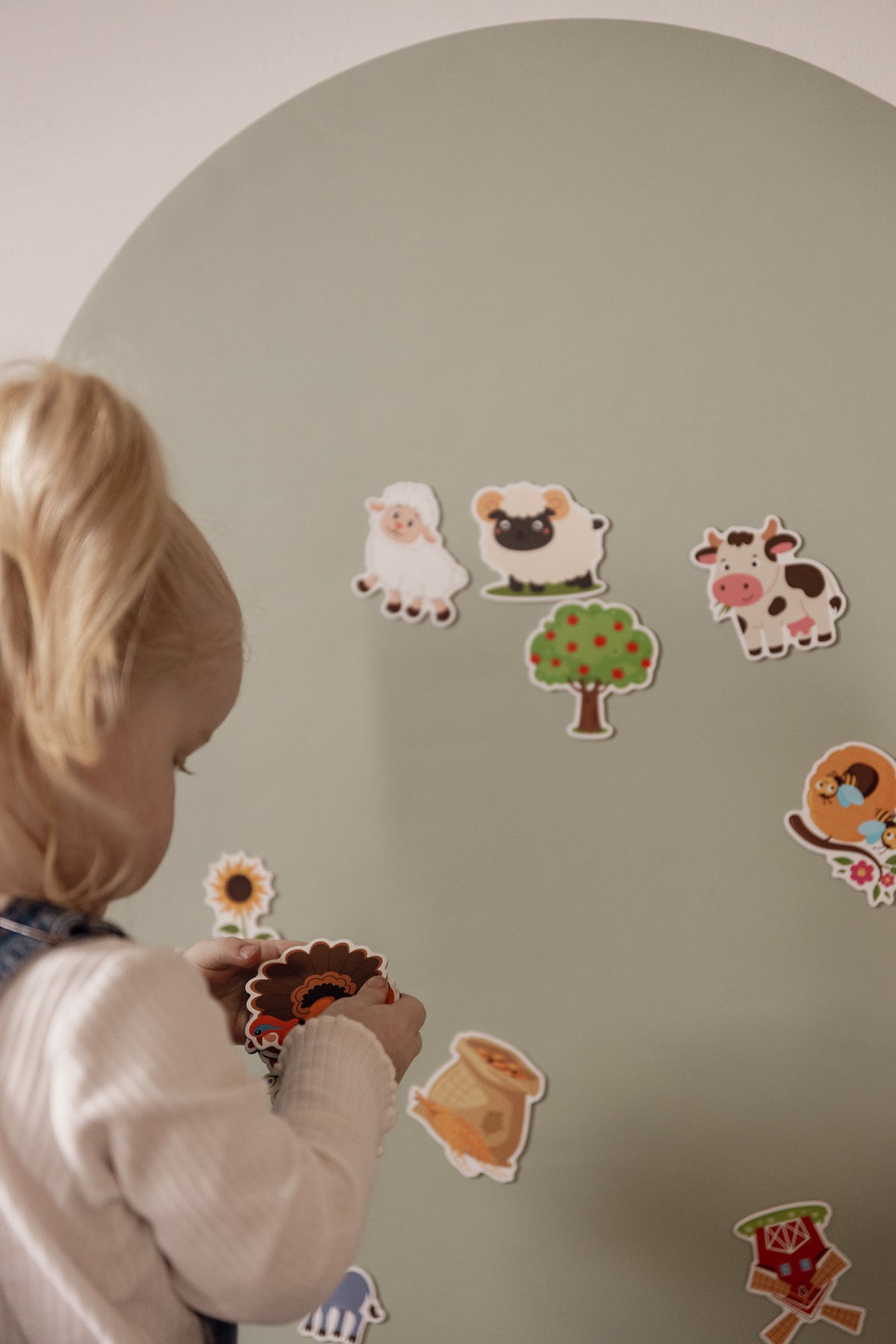 Close-up of a toddler placing farm animal magnets on the Lily Sage Wonder Arch