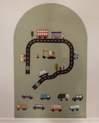 A magnetic arched wall decal featuring a children's road trip theme with a winding black road, colourful toy vehicles, and small road details.