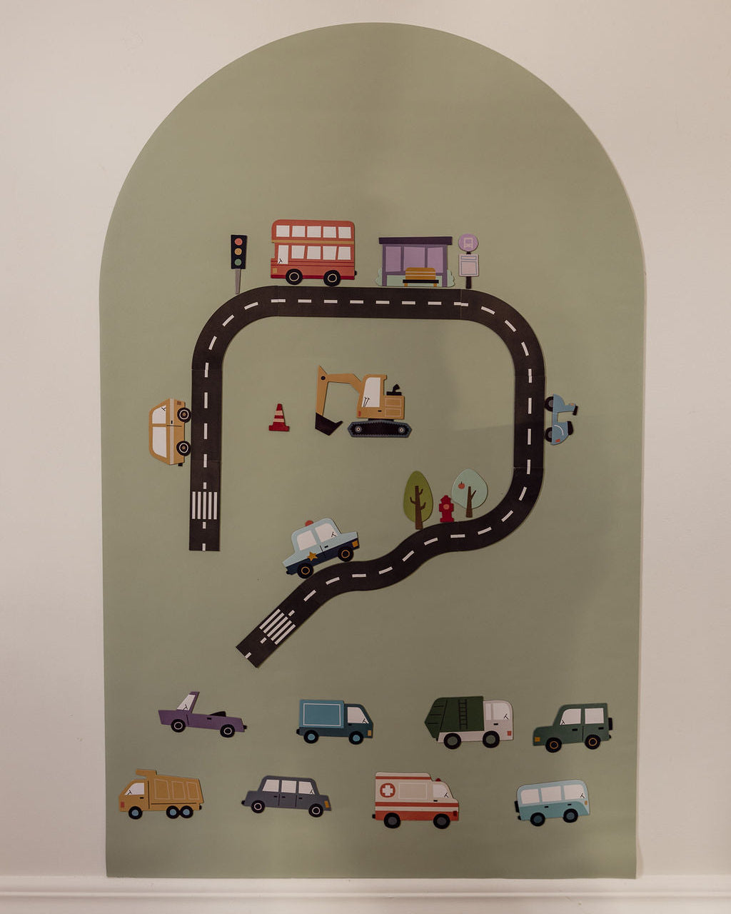 A magnetic arched wall decal featuring a children's road trip theme with a winding black road, colourful toy vehicles, and small road details.